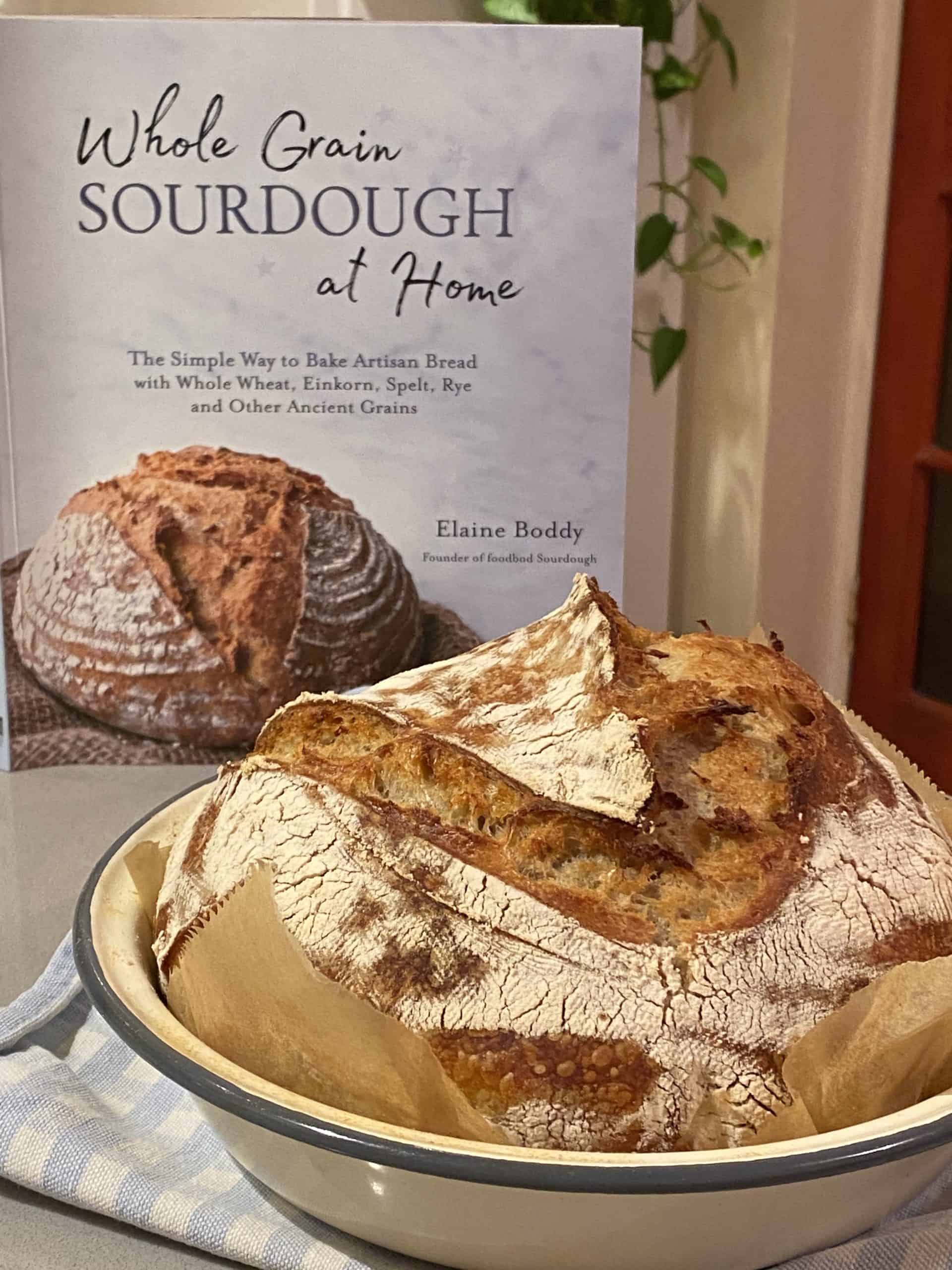 Cookbook with sourdough loaf in front of it.