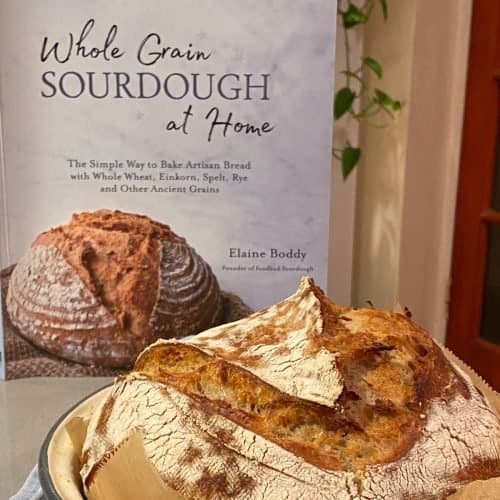 Cookbook with loaf in front of it.