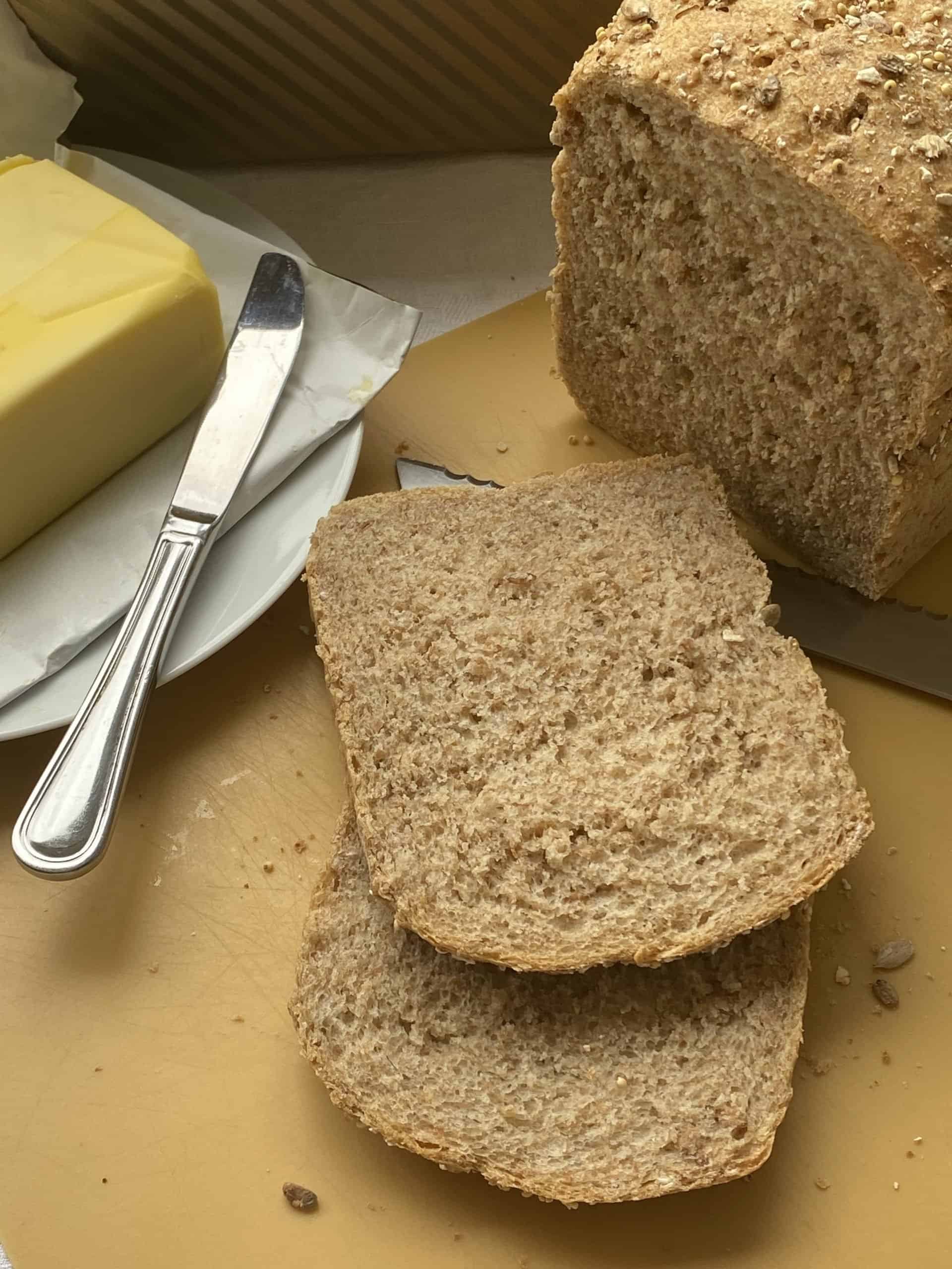 Sliced bread with plate of butter and knife in the background.