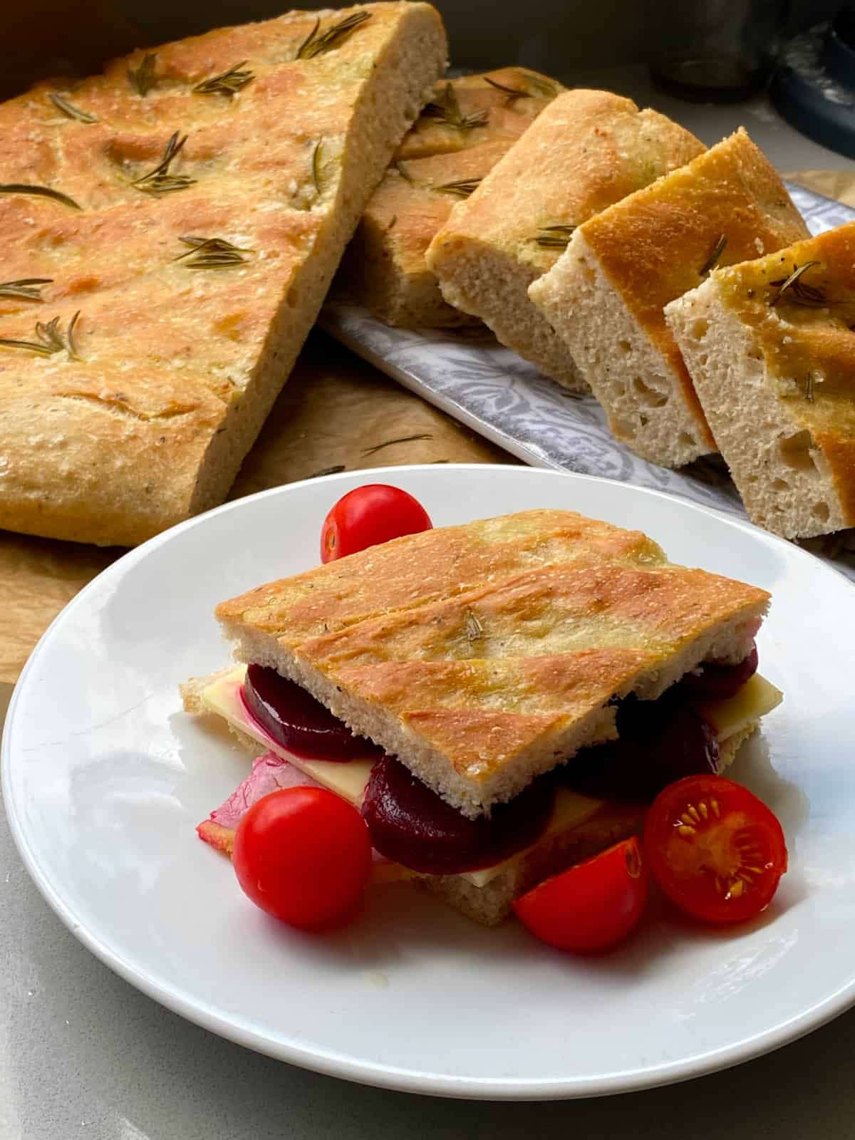 Focaccia Sandwich on a white plate with more sliced Focaccia bread in the background.