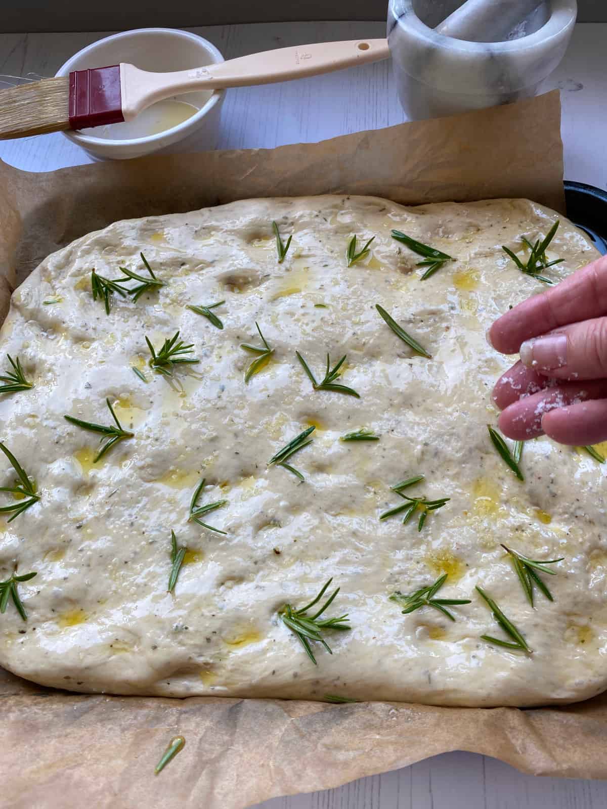 Adding the oil, salt and Rosemary to the top of the focaccia dough.