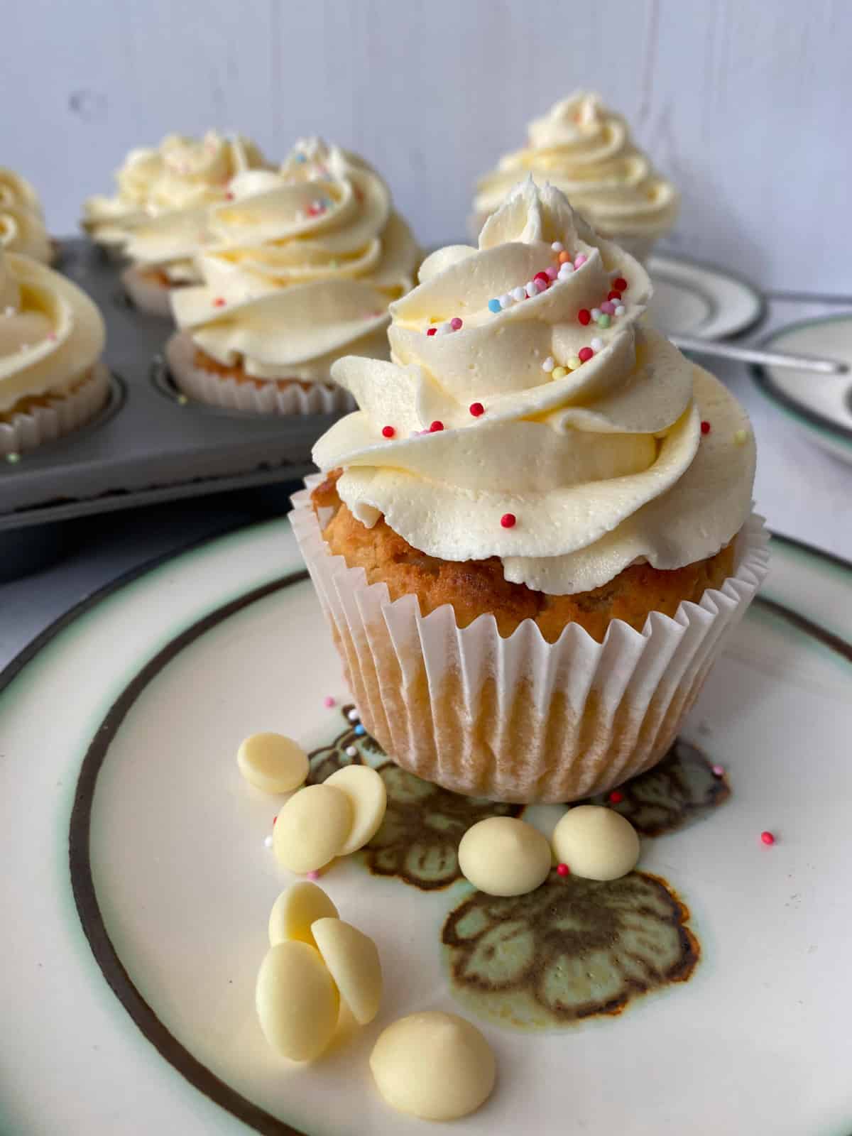 Muffin decorated with swirls of buttercream on a plate.
