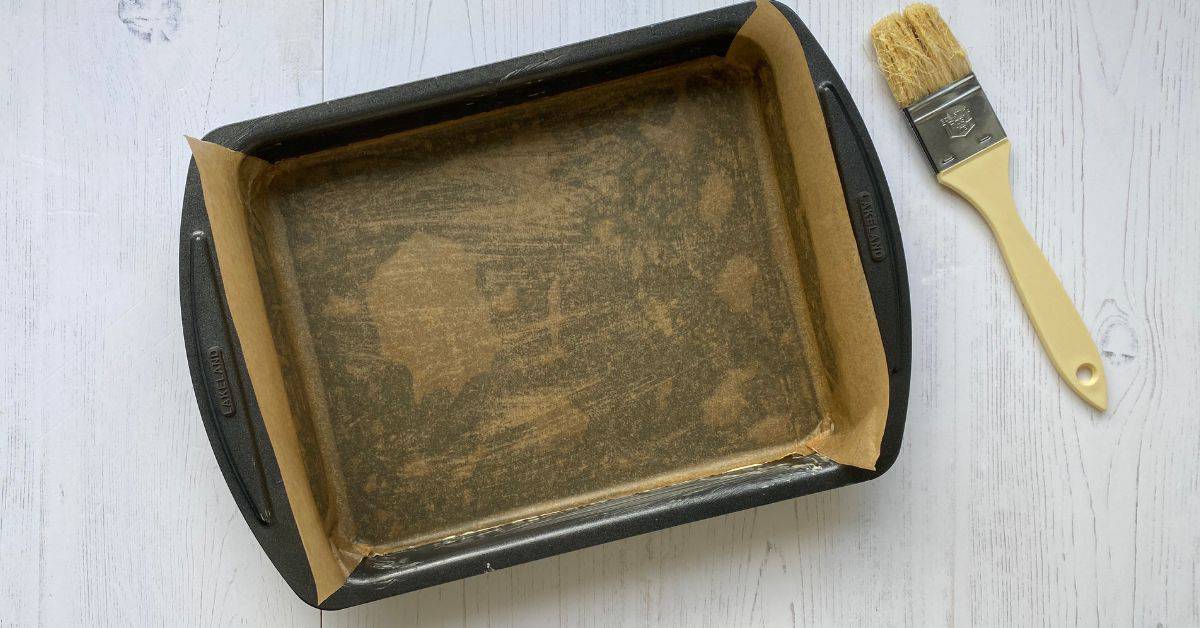 Traybake Tin lined with Baking parchment, with a pastry brush on the side.