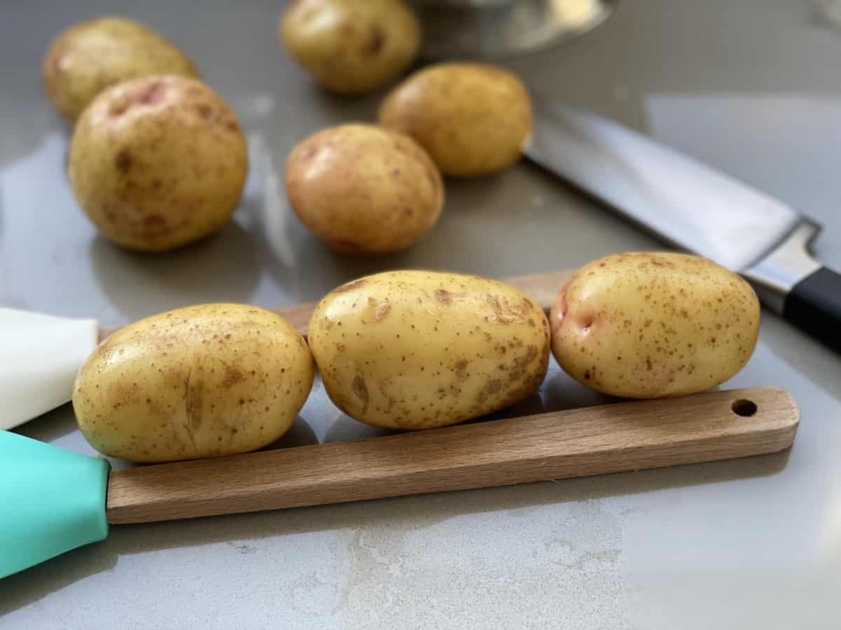 Potatoes set between wooden handles with a cutting knife on the side. 