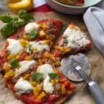 Sliced Homemade pizza on a counter top with a pizza cutter on the side.