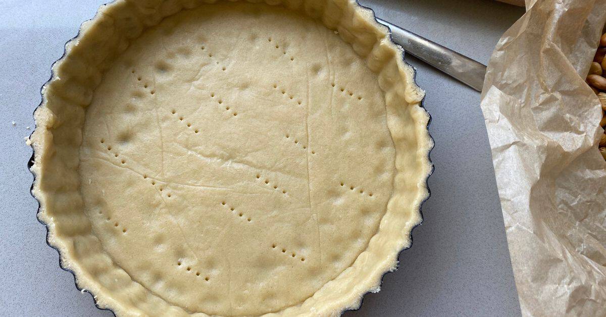 Tart tin lined with shortcrust pastry dough.