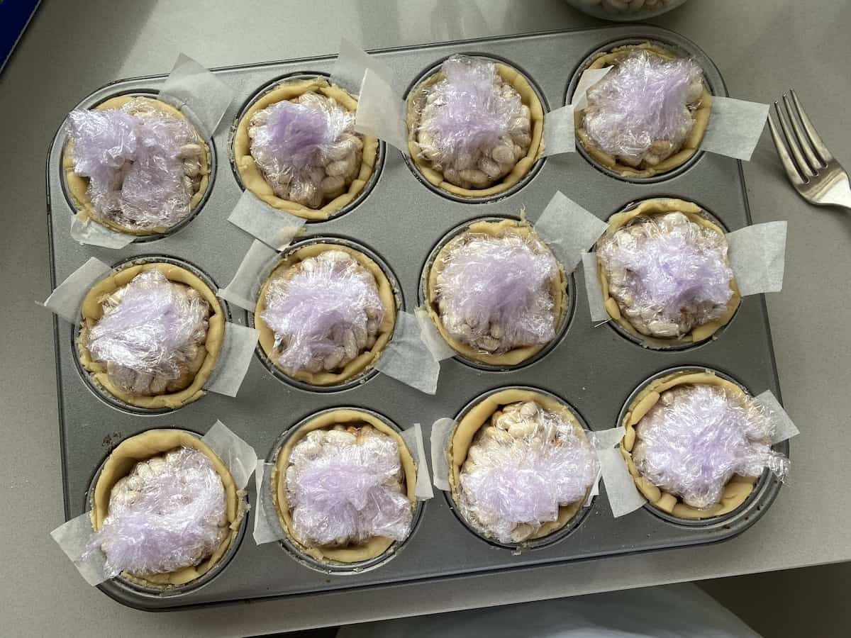 Blind baking Small pie shells in a muffin tin.